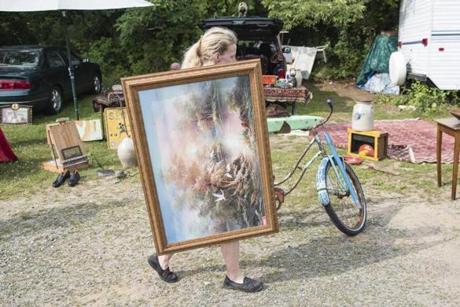 Rowley, MA - 6/30/2018 - A woman catties a painting as people shop for antiques and other items at the Todd Farm Flea Market in Rowley, MA, June 30, 2018. (Keith Bedford/Globe Staff)
