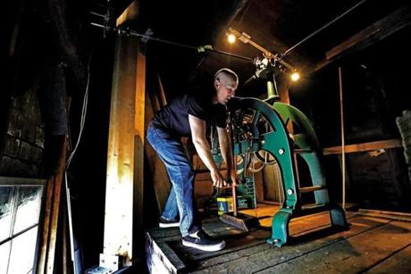 Kevin Rowe has to turn the crank handle 27 times to wind the 19th-century clock in Hingham?s New North Church.
