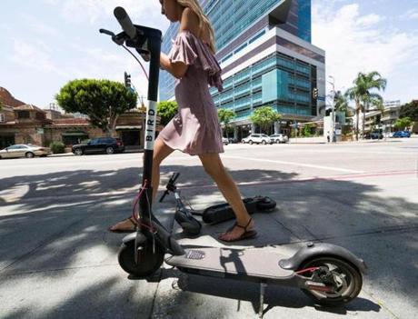 A pedestrian walks between two Bird dockless scooters in Los Angeles. 
