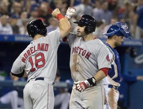 Boston Red Sox' J.D. Martinez is greeted at home plate byMitch Moreland after he hit a three-run home run against the Toronto Blue Jays during the eighth inning of a baseball game Tuesday, Aug. 7, 2018, in Toronto. (Fred Thornhill/The Canadian Press via AP)
