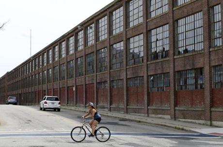Hopedale, MA--7/29/2018-- A bicyclist passes by Draper Mill in Hopedale, which the town has targeted for redevelopment after many previous failed attempts. (Jessica Rinaldi/Globe Staff) Topic: 31hopedale Reporter: 
