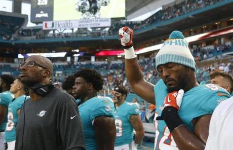 Miami Dolphins defensive end Robert Quinn (94) raises his right fist during the singing of the national anthem, before the team's NFL preseason football game against the Tampa Bay Buccaneers, Thursday, Aug. 9, 2018, in Miami Gardens, Fla. (AP Photo/Wilfredo Lee)
