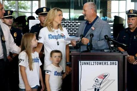 Weymouth, MA - August 23, 2018: Frank Siller, right, chief executive of Stephen Siller Tunnel to Towers Foundation delivers a mortgage payoff receipt to Cynthia ?Cindy? Chesna and her children Olivia, left, and Jack during a press conference at the Weymouth Police Department in Weymouth, MA on August 23, 2018. A New York City nonprofit has raised enough money to pay off the mortgage on the home of slain Weymouth Police Sergeant Michael Chesna. The Stephen Siller Tunnel to Towers Foundation scheduled the press conference at Weymouth Police Headquarters to present Chesna?s family with a mortgage payoff letter, said Frank Siller, chief executive of the foundation that honors his brother. (Craig F. Walker/Globe Staff) section: metro reporter:
