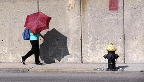 A woman shielded herself from the sun Monday morning as she walked on Dorchester Avenue in South Boston.
