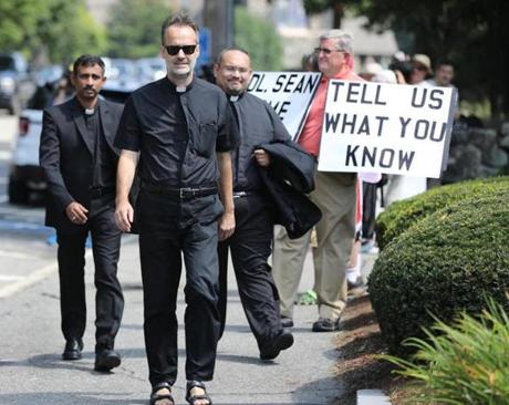 Weston, MA - 8/28/18 - Unidentified priests head toward the meeting, past protesters. Cardinal has meeting with priests at St. Julia's Parish hall, in Weston. For part of the time, people outside protest the church's handling of priest sexual abuse. Photo by Pat Greenhouse/Globe Staff Topic: 29priests Reporter: B. MacQuarrie

