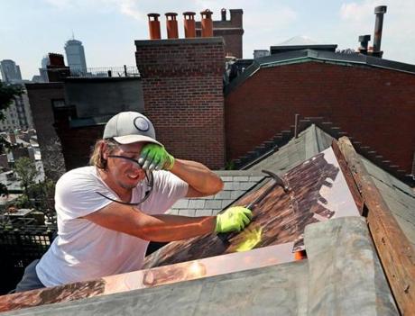 Christian Follett wiped his forehead to keep his eyes clear of sweat while working on a copper/rubber roof on Beacon Hill.
