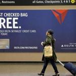 a traveler walks past a sign advertising a Delta Air Lines credit card at Seattle-Tacoma International Airport in SeaTac, Wash.