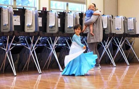 Meghan Welborn (carrying 13-month-old Bingham) voted in Milton as Alta Welborn, 3, danced nearby while dressed as Elsa from ?Frozen.?
