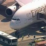 In this frame from video, a person walks off an Emirates plane at JFK International Airport to a waiting bus on Wednesday, Sept. 5, 2018, in New York, as emergency response crews gather outside the plane amid reports of ill passengers aboard a flight from Dubai. (WABC 7 via AP)