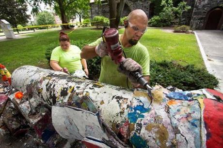 07/25/2018 - Medford/Somerville, Mass. - Josh Brown and Pam Norgustin of Warren J. Nordin & Son painting company strip thick layers of paint from the cannon on the hill on July 25, 2018. The cannon is being stripped down to the base for the first time in decades. (Alonso Nichols/Tufts University)
