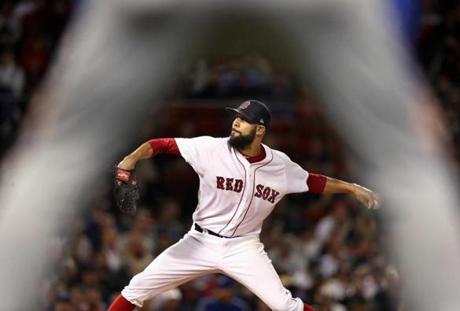 Boston, MA: 9-12-18: Framed by the legs of Toronto firstbase coach Tim Leiper, Red Sox starting pitcher David Price fires a seventh inning pitch. The Boston Red Sox hosted the Toronto Blue Jays in a regular season MLB baseball game at Fenway Park. (Jim Davis/Globe Staff)
