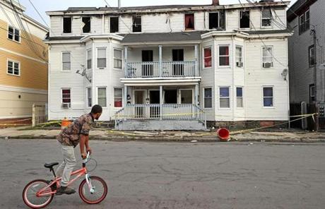 A bicyclist rode past a damaged house on Springfield Street Lawrence.
