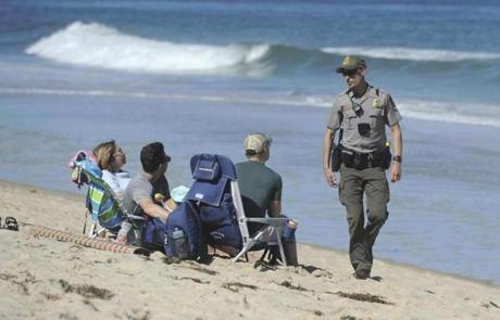 Cape Cod National Seashore Park Ranger Eric Trudeau walks up to a group of visitors on Newcomb Hollow Beach telling them that the beach is closed to swimming, Saturday, Sept. 15, 2018, in Wellfleet, Mass. Trudeau was walking up and down the beach alerting people to the beach closure after a Revere man was bitten and died from a shark bite Saturday off Newcomb Hollow Beach. (Merrily Cassidy/The Cape Cod Times via AP)
