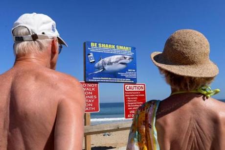Wellfleet-09/16/18 Beachgoers pause at warning signs at th entrance to Newcomb Hollow Beach in Wellfleet on Sunday, a day after Arthur Medici was killed by a shark Saturday while boogie boarding.Photo for Boston Globe by Debee Tlumacki(metro)
