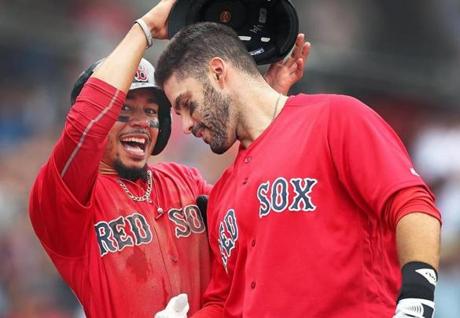 Boston, MA: 9-26-18: The Red Sox Mookie Betts removes the helmet of teammate J.D. Martinez as he heads into the dugout following his three run home run in the bottom of the fourth inning.The Boston Red Sox hosted the Baltimore Orioles in the first game of a day-night MLB baseball doubleheader at Fenway Park (Jim Davis/Globe Staff) 
