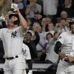 New York Yankees ' Giancarlo Stanton, left, and center fielder Aaron Hicks celebrate after scoring on an RBI triple by Luke Voit against the Oakland Athletics during the sixth inning of the American League wild-card playoff baseball game, Wednesday, Oct. 3, 2018, in New York. (AP Photo/Bill Kostroun)