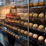 Red Sox curator is reflected in the display case of a collection of World Series baseballs at Fenway Park.