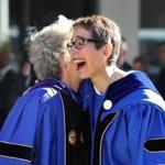 Suffolk University?s president Marisa Kelly is greeted by a fellow staff member during Friday?s ceremony.