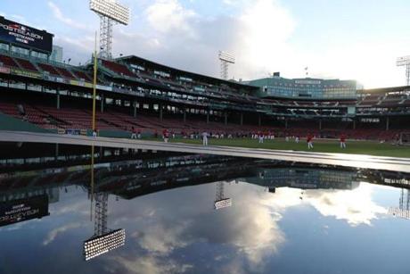 Boston, MA 10/13/18: Red Sox players warm up (background) while Fenway is reflected over a water spot above the dugout. Boston Red Sox hosted the Houston Astros in Game One of ALCS at Fenway Park Saturday, Oct. 13, 2018. (John Tlumacki/Globe Staff)
