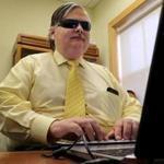 Brian Charlson, who was blinded at age 11, typed on a Braille keyboard in his office at the Carroll Center for the Blind in Newton. 