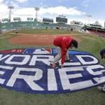 Grounds crew members paint the World Series logo behind home plate at Fenway Park, Sunday, Oct. 21, 2018, in Boston as they prepare for Game 1 of the baseball World Series between the Boston Red Sox and the Los Angeles Dodgers scheduled for Tuesday. (AP Photo/Elise Amendola)