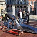 Chris Gromek used his back to lift about 800lbs of spoon, along with artist Domenic Esposito (left) and Spoon Movement gallery owner Fernando Alvarez (in hat), outside the State House Friday. 