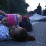 A mother and daughter rest on the roadside as a thousands-strong caravan of Central Americans continues its slow march toward the U.S. border, near Tapanatepec, Oaxaca state, Mexico, before dawn on Monday, Oct. 29, 2018. Thousands of migrants traveling together for safety resumed their journey after taking a rest day Sunday, while hundreds more migrants were pushing for entry to Mexico.(AP Photo/Rebecca Blackwell)