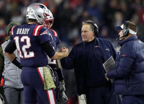 Foxborough, MA: 11-4-18: Patriots quarterback Tom Brady (12,left) gets a hand from head coach Bill Belichick as the clock was running down in the New England victory over the Packers. Offensive coordinator Josh McDaniels is at far right. The New England Patriots hosted the Green Bay Packers in an NFL regular season Sunday night football game at Gillette Stadium. (Jim Davis/Globe Staff) 
