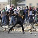FILE -- In this Oct. 2, 2018 file photo, a Palestinian protester from Birzeit University throws stones during clashes with Israeli troops near the Jewish settlement of Beit El, near the West Bank city of Ramallah. President Donald Trump?s assertion that stones thrown by Latin American protesters at American troops should be treated as ?rifles? has sparked debate about the appropriate response to rock throwing crowds -- particularly after Nigerian troops appeared to use his comments as justification for a deadly crackdown on demonstrators. From the Gaza Strip to Africa to Europe, security forces have long dealt with stone throwers, albeit in very different ways. (AP Photo/Majdi Mohammed, File)