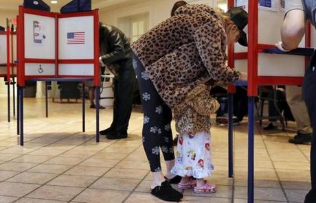 MIDTERMS SLIDER Falcon Wien, age 2 1/2, huddles under the coat of her mother, Sarah Wien, as she votes at the Presbyterian Church of Mount Kisco, in Mt. Kisco, N.Y. Tuesday, Nov. 6, 2018. (AP Photo/Richard Drew)
