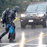 In pouring rain, wearing a dry suit, diver Roy Mennell crossed Washington St. in Gloucester. 