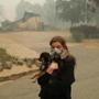 Araya Cipollini, 19, holds on to her dog T.J. near the burned out remnants of her neighbor's home in Paradise, Calif., Saturday. Cipollini and her family lost their home nearby in the fire. 