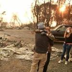 Kimberly Spainhower hugged husband Ryan while daughter Chloe looked on near the burned remains of their home in Paradise, Calif. 