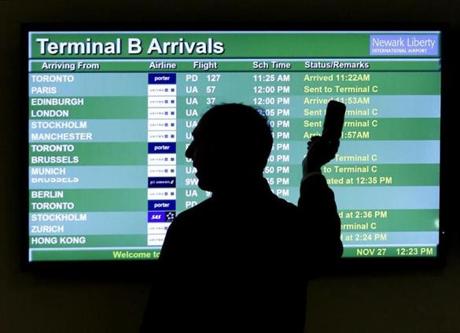 FILE - In this Nov. 27, 2013, file photo, a person points to a screen with an airplane travel list while holding up a phone at Newark Liberty International Airport in Newark, N.J. International air travel has become remarkably safe in recent years, with deadly accidents like last month's Lion Air crash in Indonesia becoming more rare. (AP Photo/Julio Cortez, File)
