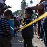 TOPSHOT - Two boys among a group of Central American migrants - mostly from Honduras - moving towards the United States, are seen lining up for food outside a temporary shelter at the US-Mexico border in Tijuana, Baja California state, Mexico, on November 23, 2018. - After a trek of more than a month from Honduras, nearly 5,000 migrants have been living in a makeshift shelter fashioned from an open air sports arena. (Photo by Guillermo Arias / AFP)GUILLERMO ARIAS/AFP/Getty Images
