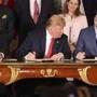 President Donald Trump, center, looks over at Canada's Prime Minister Justin Trudeau's document as they and Mexico's President Enrique Pena Nieto sign a new United States-Mexico-Canada Agreement that is replacing the NAFTA trade deal.