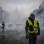 PARIS, FRANCE - DECEMBER 01: Teargas surrounds protesters as they clash with riot police during a 'Yellow Vest' demonstration near the Arc de Triomphe on December 1, 2018 in Paris, France. The third 'Yellow Vest' (gilets jaunes) rally in Paris over increased fuel taxes and leadership in the government today caused over 150 arrests in the city with reports of injuries to protesters and security forces from violence that irrupted from the clashes. (Photo by Veronique de Viguerie/Getty Images)
