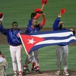 FILE - In this Monday, May 3, 1999 file photo, members of the Cuban baseball team carry their country's flag onto the field after a baseball game against the Baltimore Orioles at Camden Yards in Baltimore. Major League Baseball, its players? association and the Cuban Baseball Federation reached an agreement that will allow players from the island nation to sign big league contracts without defecting, an effort to eliminate the dangerous trafficking that had gone on for decades. The agreement runs through Oct. 31, 2021. (AP Photo/Nick Wass, File)