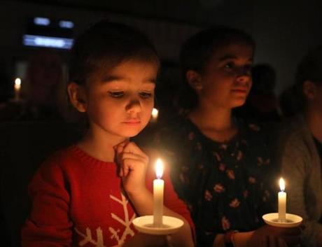 Watertown, MA - 12/24/18 Sophia Biggins (cq), 4, left, studies her candle's flame near the end of the service. At right is Aubrey Croak (cq), 9. Grace Chapel Watertown holds it's first of two Christmas eve candlelight services. Photo by Pat Greenhouse/Globe Staff Topic: 25christmaseveserviceMetro
