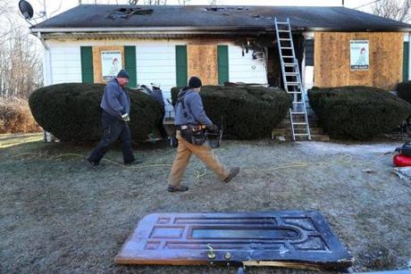 Workers secured the home at 52 Freeman Street in Avon where two men died in a fire Tuesday night. The home?s front door was left on the front lawn. 
