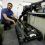 In this Aug. 28, 2018 photo, software engineer Nicholas Otero, of Woburn, Mass., speaks with a colleague about features on a Centaur robot, right, at Endeavor Robotics in Chelmsford, Mass. The Army is looking for a few good robots. These robots won?t fight, at least not yet. But they will be designed to help the men and women who do. The companies making them are waging a different kind of battle. At stake is a contract worth almost half a billion dollars for 3,000 backpack-sized robots that can defuse bombs and scout enemy positions. (AP Photo/Steven Senne)