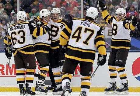 Boston Bruins center Patrice Bergeron (37), center, celebrates with teammates after scoring his goal in the second period of the NHL Winter Classic hockey game against the Chicago Blackhawks at Notre Dame Stadium, Tuesday, Jan. 1, 2019, in South Bend, Ind. (AP Photo/Nam Y. Huh)
