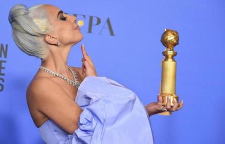Lady Gaga poses in the press room with the award for best original song from a motion picture.
