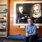 01/01/2019 CAMBRIDGE, MA Founder James Graham (cq) at Community Phone in Cambridge. A poster behind him displays portraits of Thomas Watson (cq) (left) and Alexander Graham Bell (cq). (Aram Boghosian for The Boston Globe)