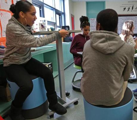 Eighth-grader Sarai Rosa, seated on a wobble stool, adjusted a desk so she could stand at the Joseph Lee K-8 School.
