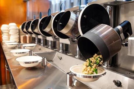 An automated wok dumps finished food into bowl at Spyce in Boston.
