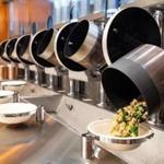 An automated wok dumps finished food into bowl at Spyce in Boston.