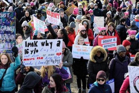 People hold signs and cheer during the 2019 Women's March at Boston Common.
