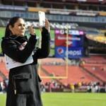 CBS sportscaster Tracy Wolfson takes picture of the field prior to an NFL football game between the Dallas Cowboys and Washington Redskins, Sunday, Oct. 21, 2018, in Landover, Md. (AP Photo/Mark Tenally)