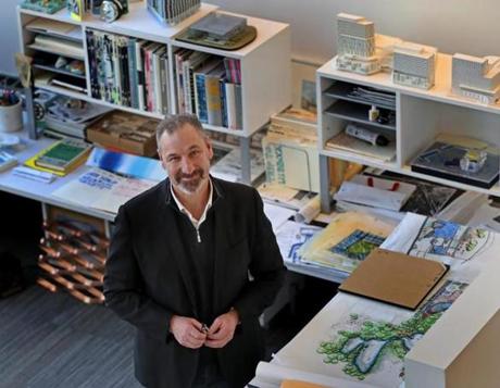 Marc Rogers of Cambridge Seven Architects has his busy desk in a corner with windows offering a view of Cambridge.
